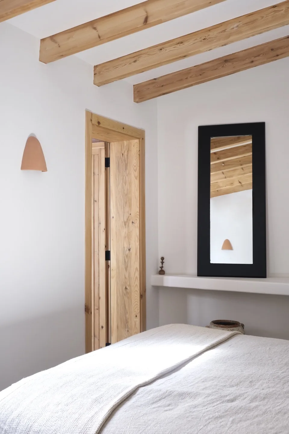 Paraíso — bedroom with wooden beams, terracotta sconce, and linen bedding