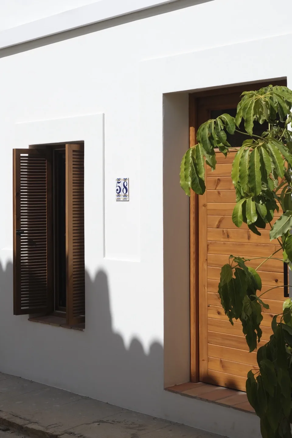 Paraíso — white facade with number 58 ceramic tile, wooden door, and shutters