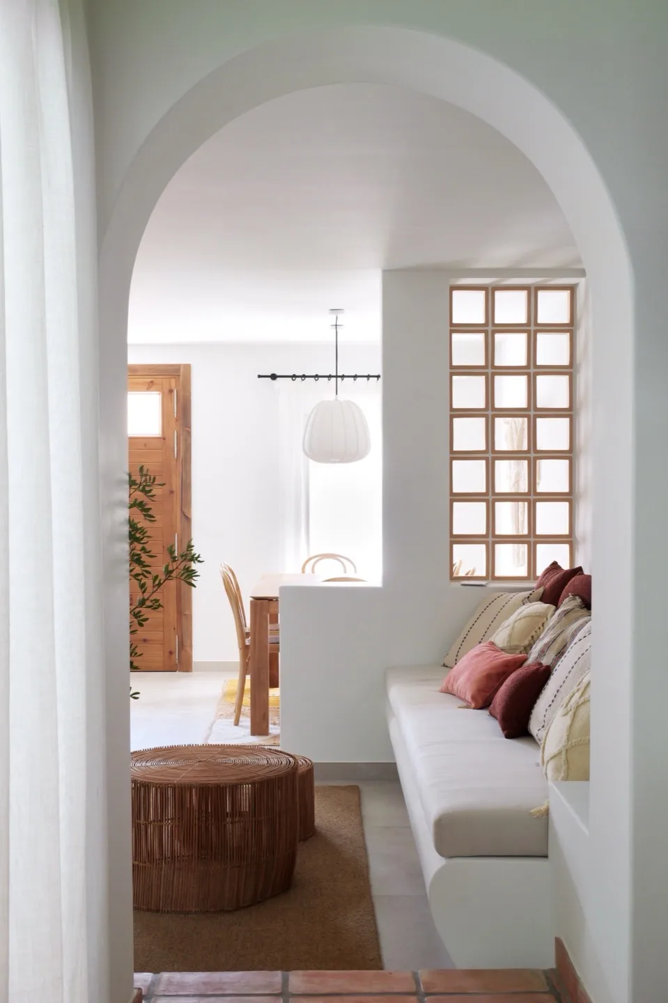 Paraíso — through-arch view of living and dining areas with grid window